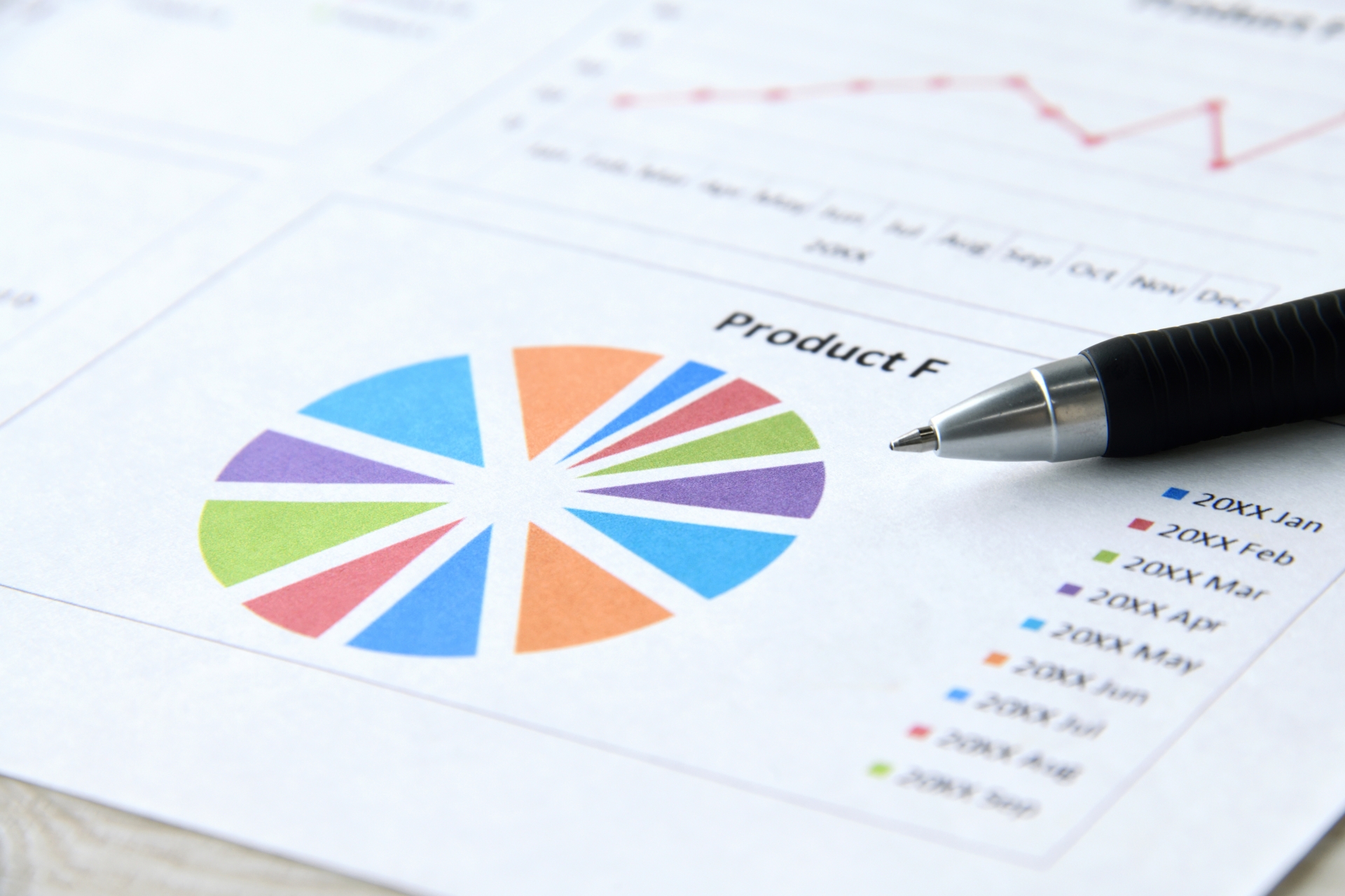 A pen rests on top of a colourful pie chart, perhaps indicating sales growth or a marketing and PR strategy.