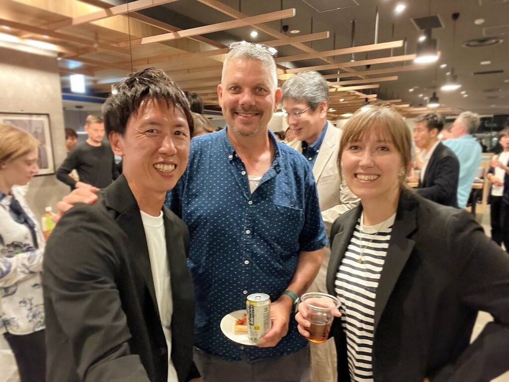 Three smiling people stand together at a networking event.