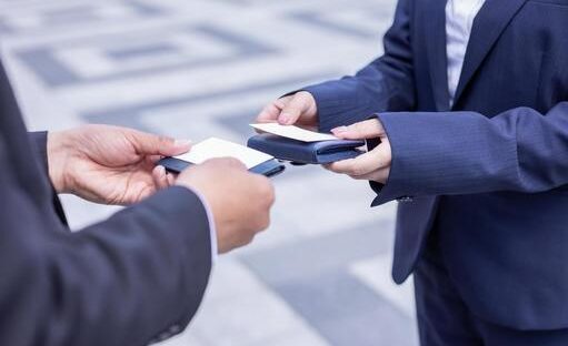 Two business people exchange business cards.